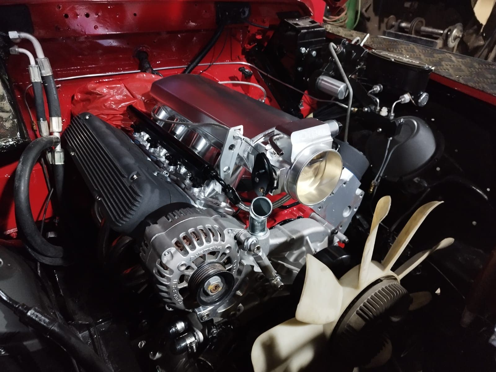 El LS 5.3 instalado en el compartimiento rojo del Land Rover Defender, con la tapa del múltiple pintada a juego y la admisión pulida