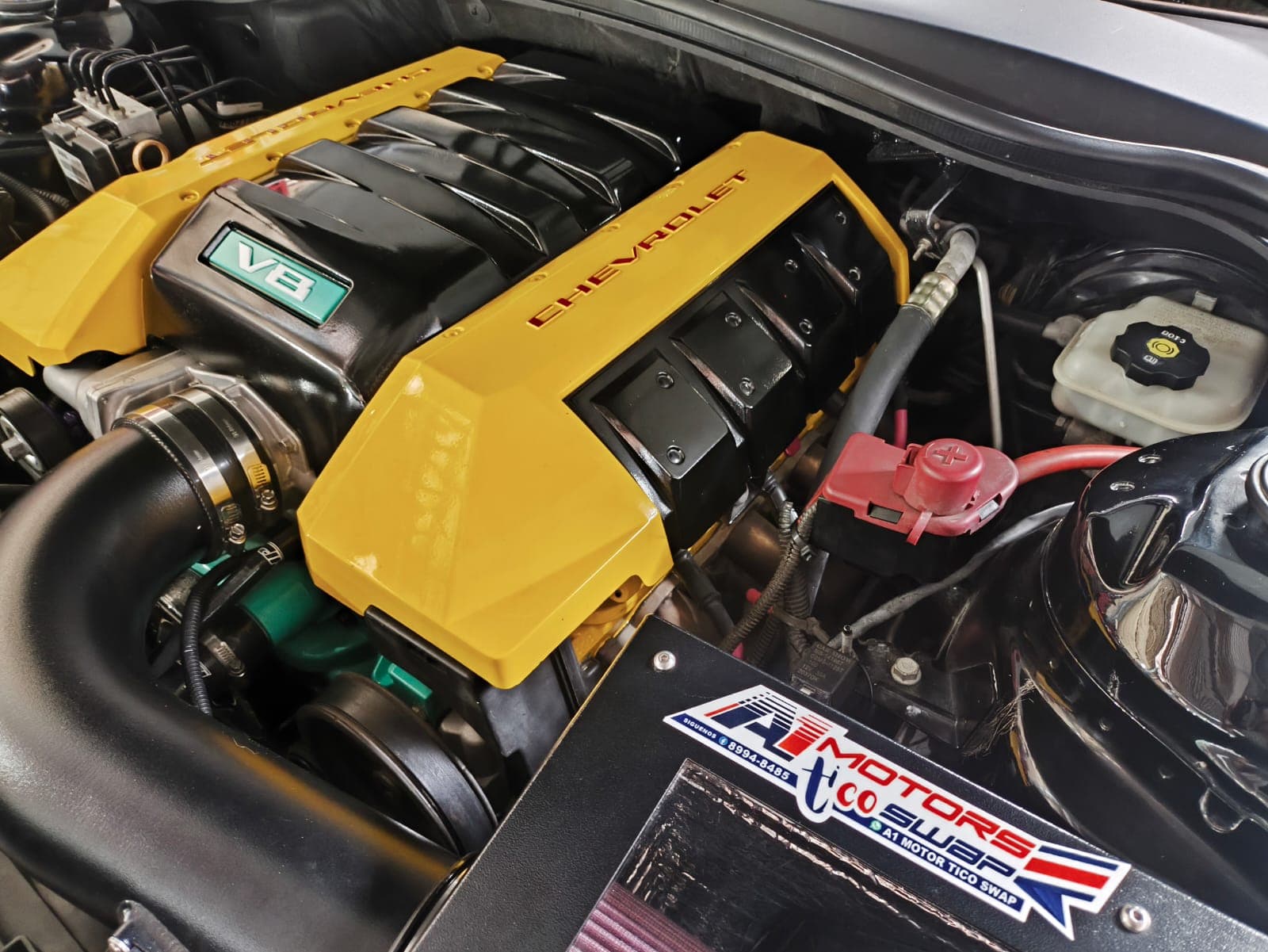 Primer plano del múltiple de admisión del LS3 con las tapas Chevrolet pintadas de amarillo y el emblema V8