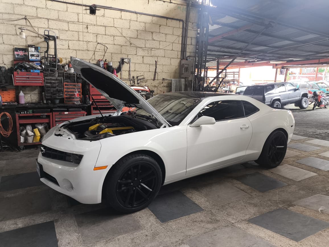 Chevrolet Camaro 2012 repintado de blanco con el capó abierto en el taller, ya con el swap a LS3 terminado