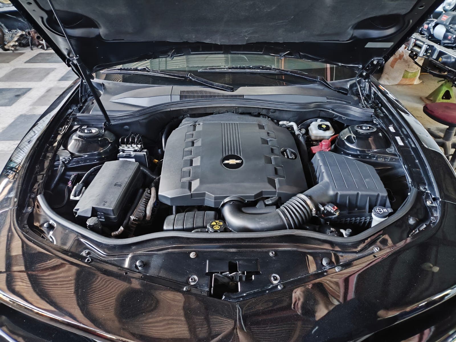 Compartimiento de motor de un Chevrolet Camaro 2012 negro con el V6 3.6 de fábrica, su tapa plástica y la caja de aire original