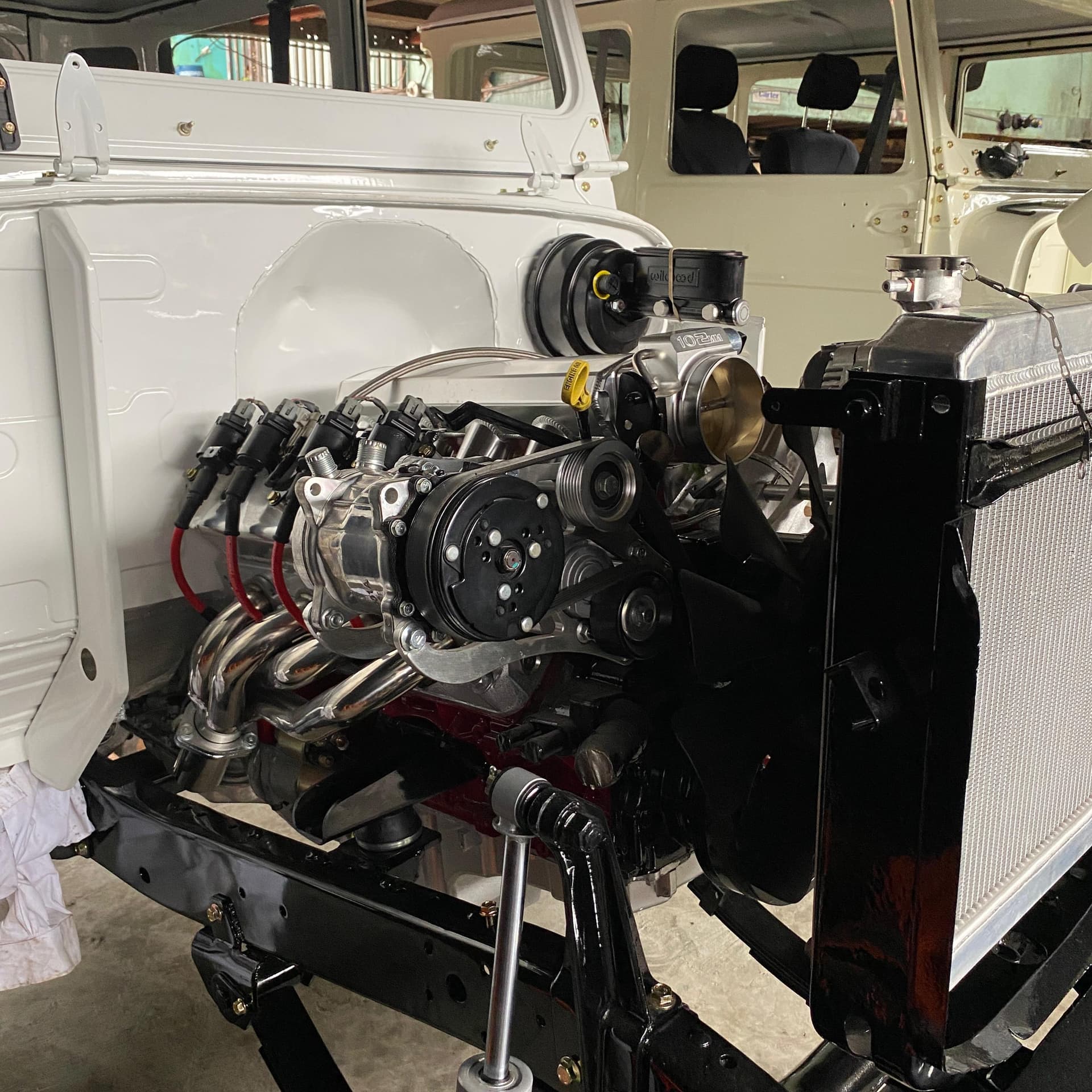 El LS 5.3 instalado en el frente del Land Cruiser BJ40 con la carrocería blanca desarmada, múltiples tipo header pulidos, radiador de aluminio y bomba de frenos Wilwood