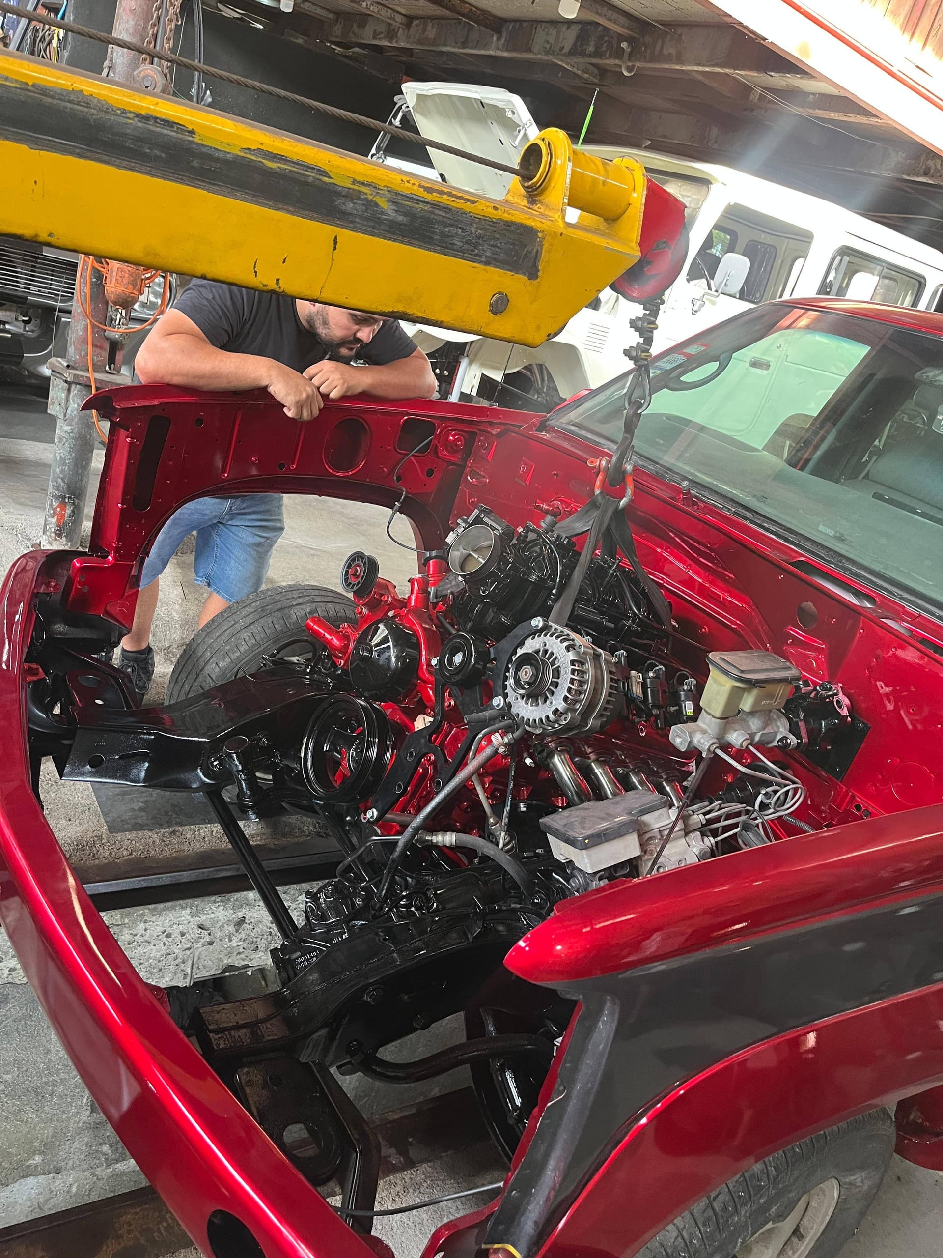 Bajando el LS2 al compartimiento del Tahoe con el frente desarmado, con un mecánico guiando el motor desde el tecle