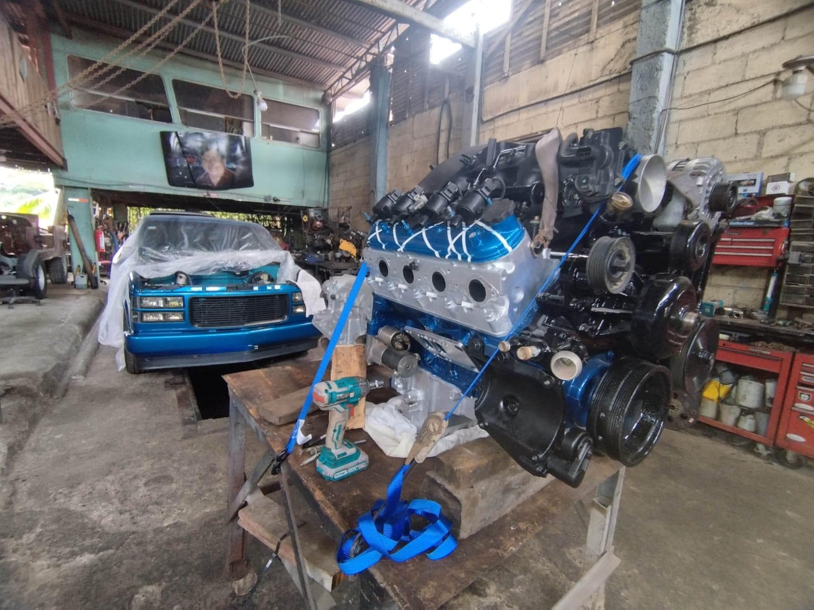 El motor LS 6.0 armado sobre la mesa de trabajo, con el bloque pintado de azul y las culatas en aluminio, con la pick up cubierta al fondo