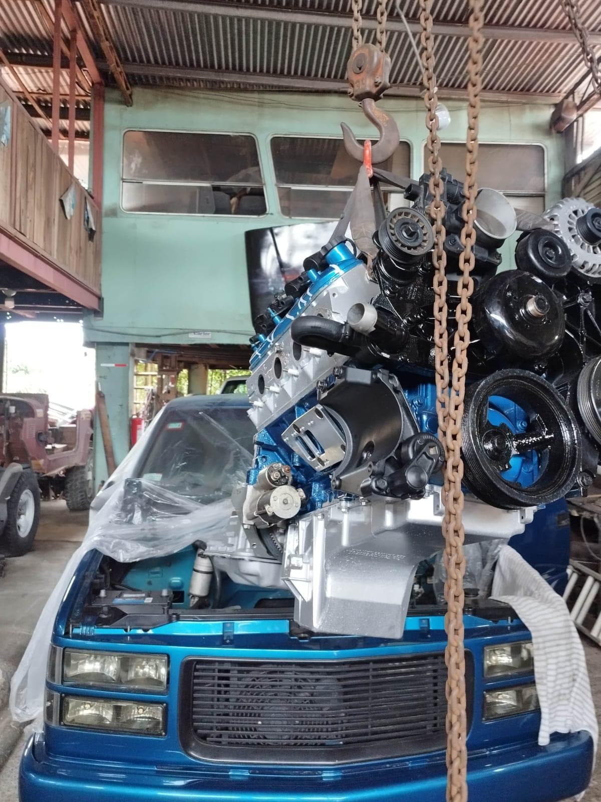 El LS 6.0 colgando de la cadena del tecle sobre el frente de la pick up Chevrolet azul, listo para bajarlo al compartimiento