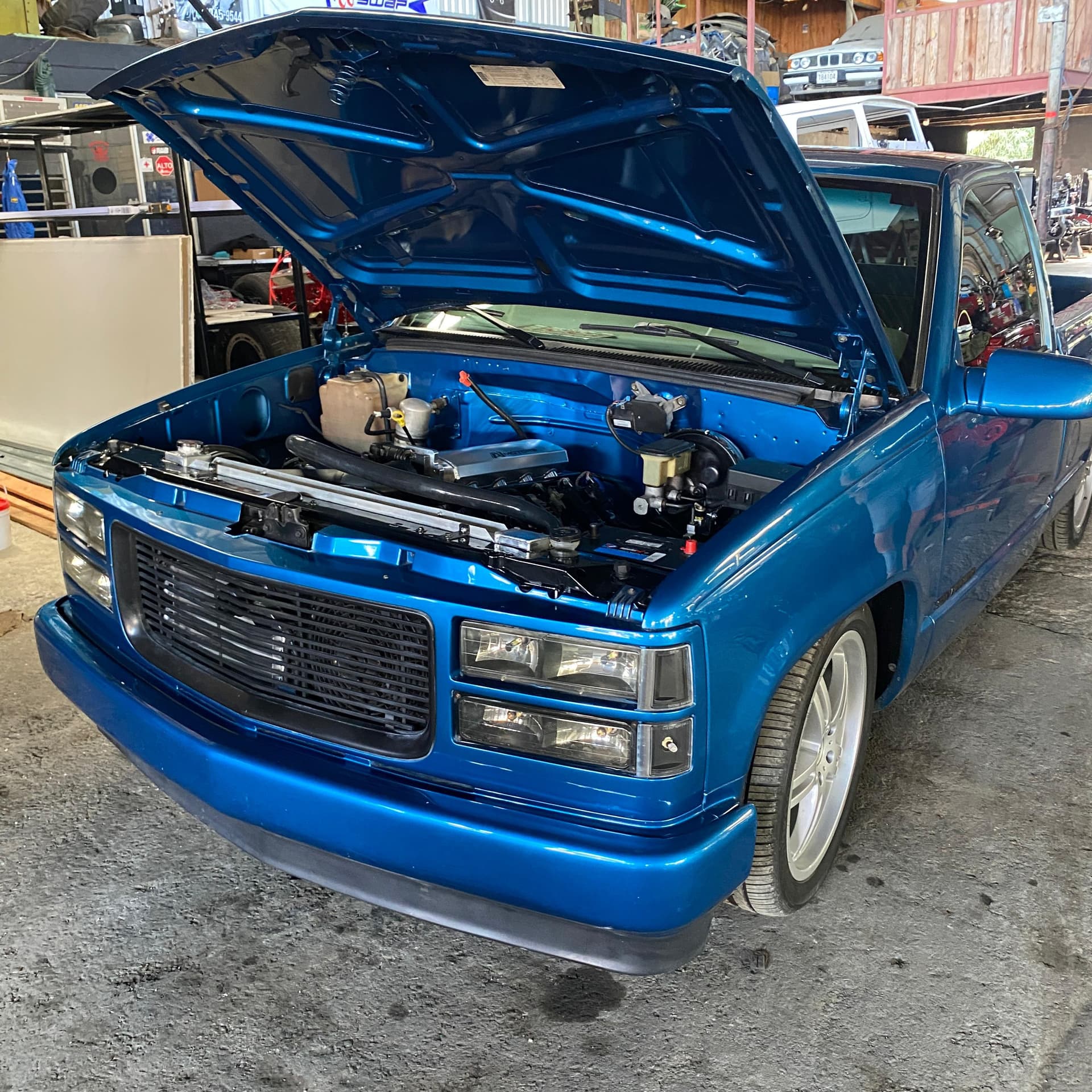 Pick up Chevrolet azul bajada de suspensión, con el capó abierto en el taller de A1 Motors Tico Swap después del swap a LS 6.0