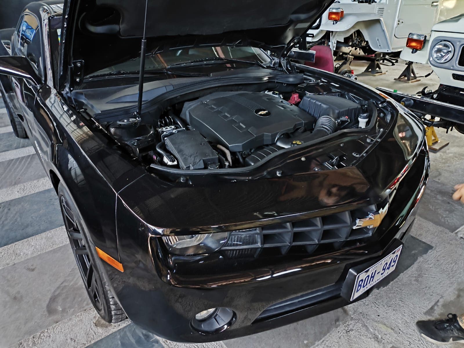 Frente del Chevrolet Camaro negro con el capó abierto, mostrando el V6 3.6 original antes del swap a LS3