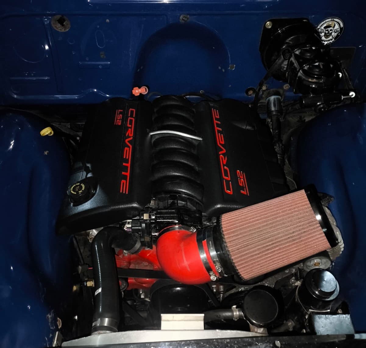 El mismo compartimiento azul de la pickup Chevrolet de 1952 con el V8 LS2 de Corvette instalado, tapas negras con letras rojas, tubo de admisión rojo y filtro cónico